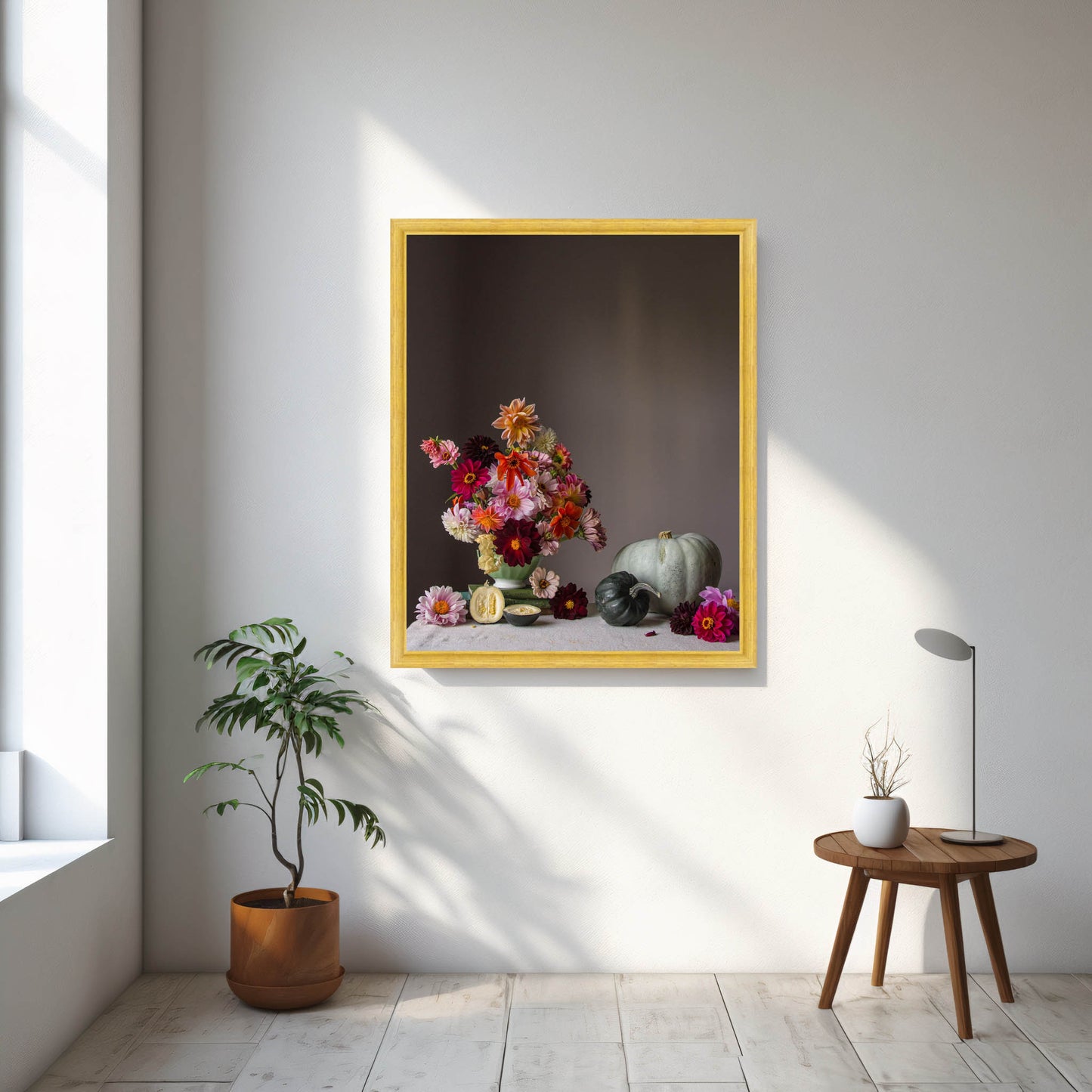 Framed floral artwork on a wall with a plant and small table in the foreground. Flower photograph.