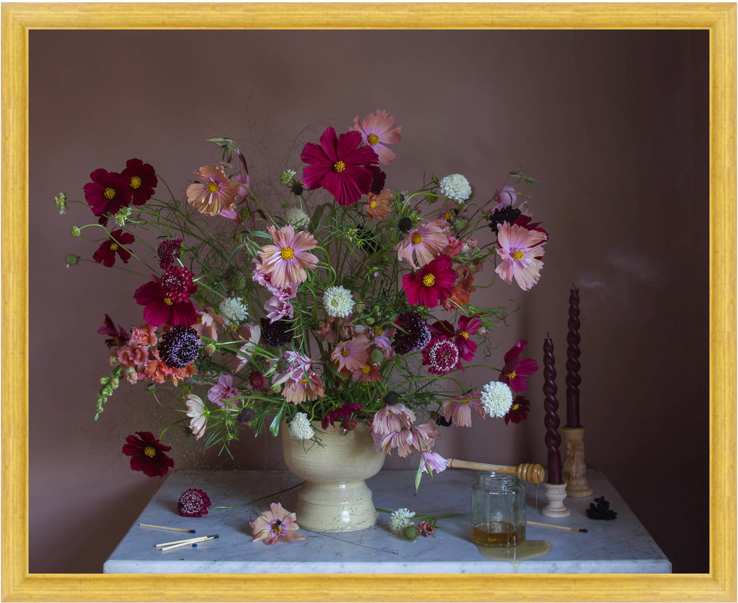 Framed still life arrangement with flowers and candles on a table against a dark background