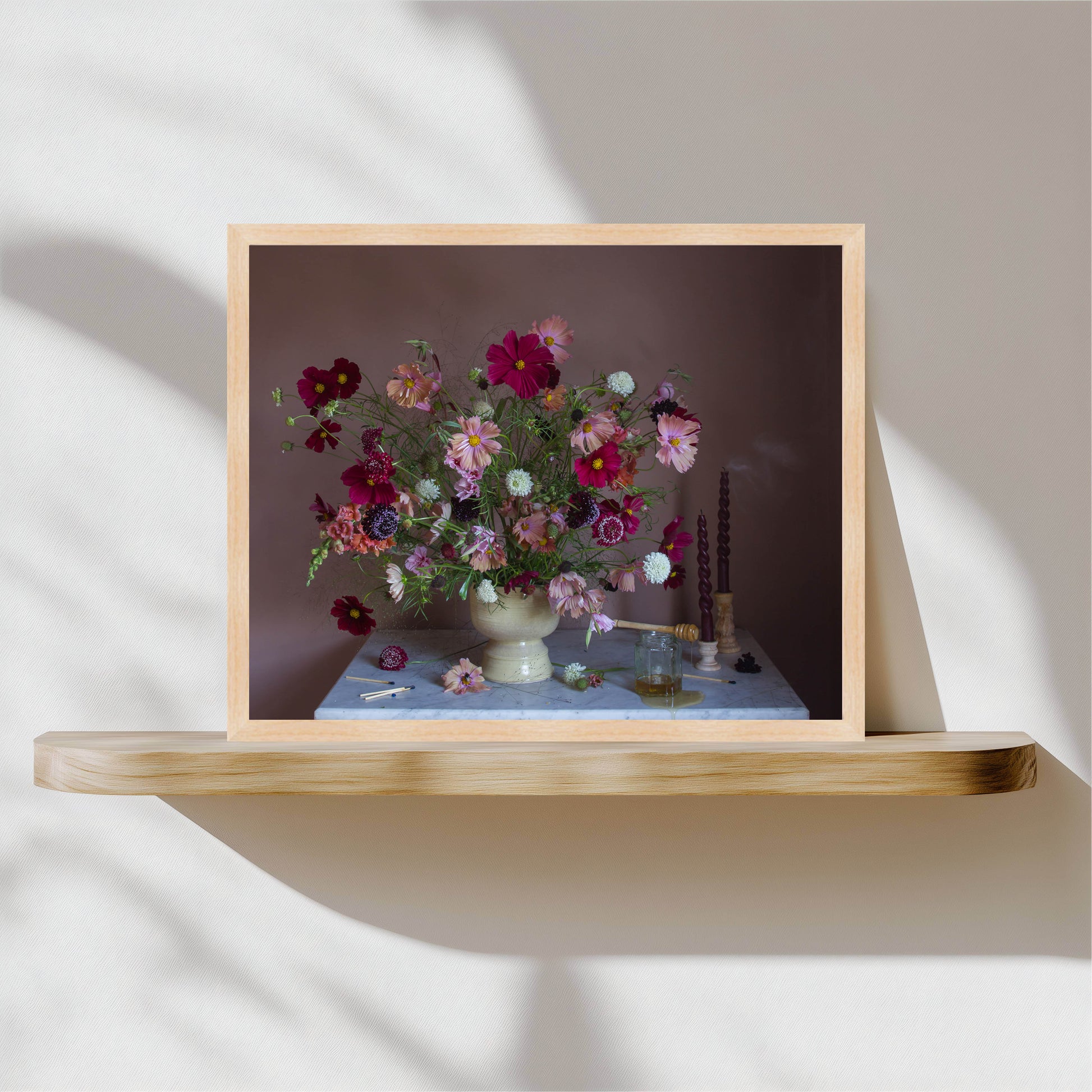 Framed photograph of a floral arrangement on a wooden shelf with a neutral background