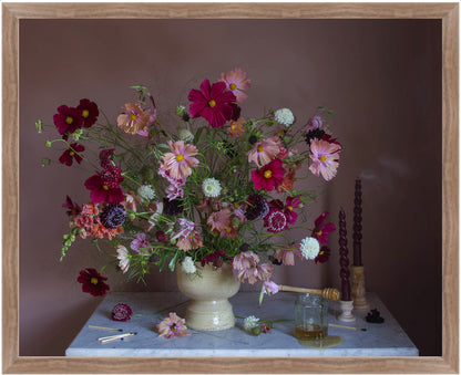 Fine art photograph of flowers on a table with candles and a honey jar against a dark background