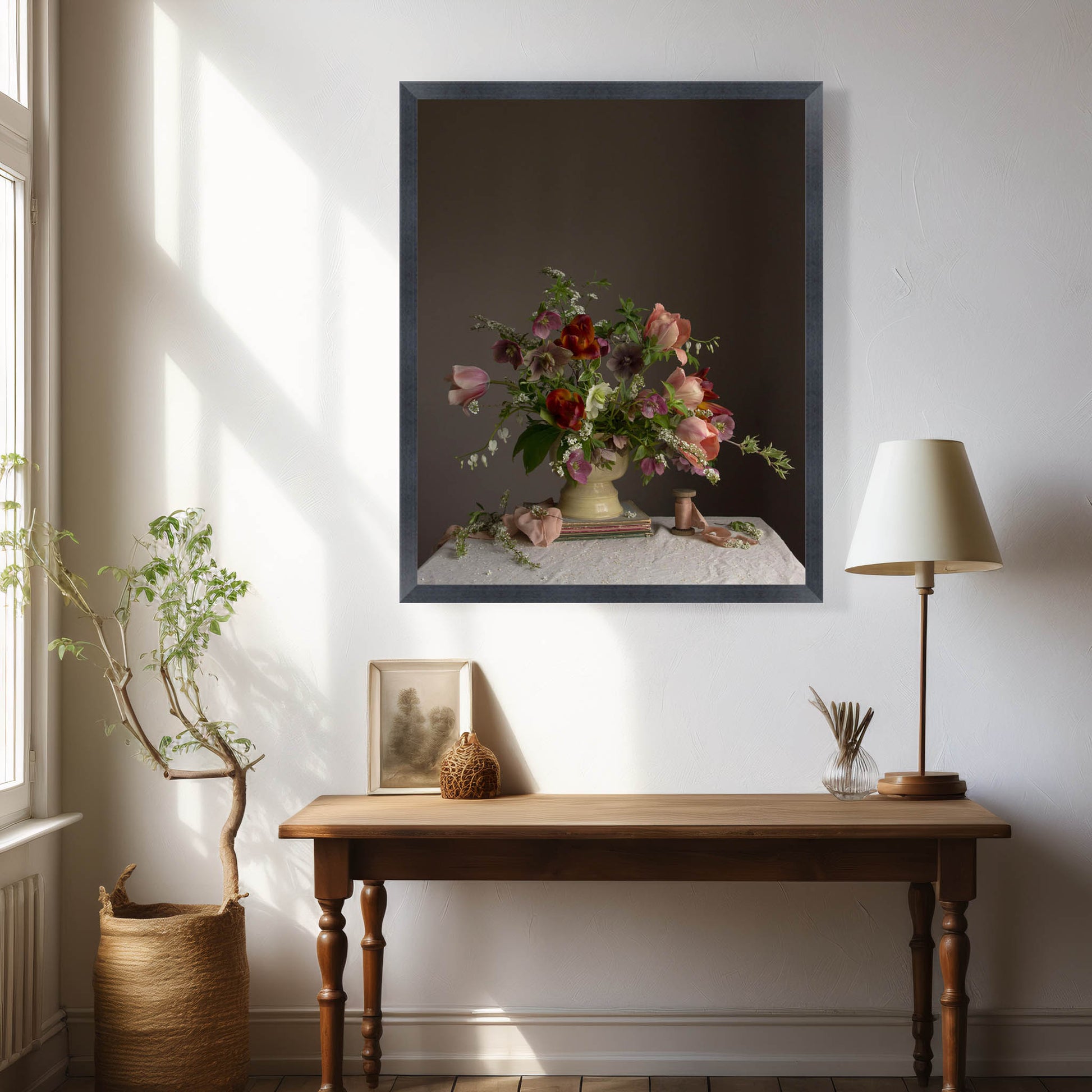 Room interior with a wooden table, lamp, and framed artwork on a white wall.  Floral photograph