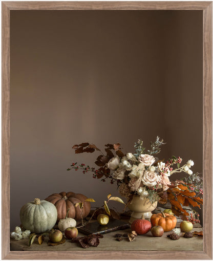 Framed floral art with pumpkins and flowers on a wooden surface against a brown background