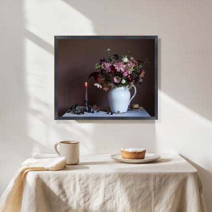 Framed artwork of a still life with flowers and candles on a tablecloth.