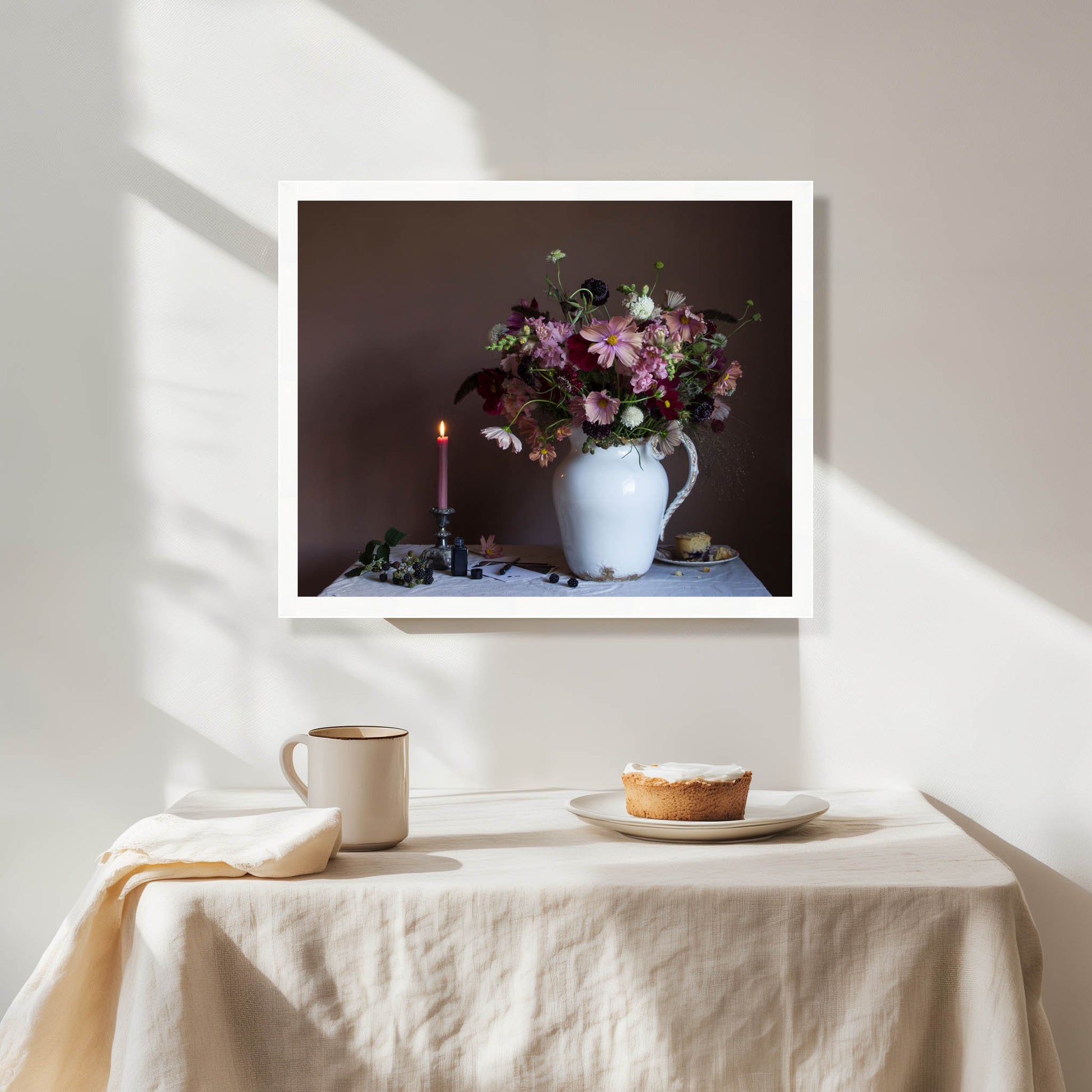 Framed photograph of a still life scene with flowers, candle, and pie on a table.