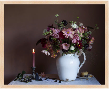 Framed still-life showing a floral arrangement in a white pitcher with a lit candle and small plate on a dark background