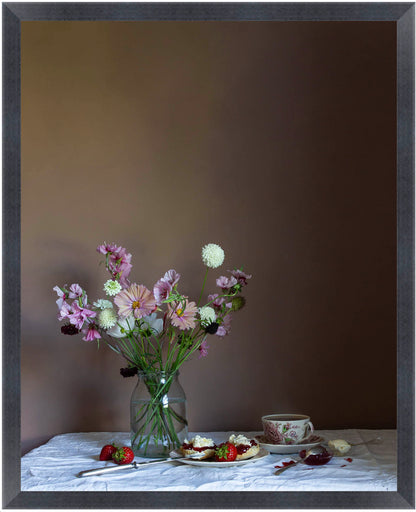 Framed still life scene with flowers in a vase, a teacup, and a plate on a table against a dark background.