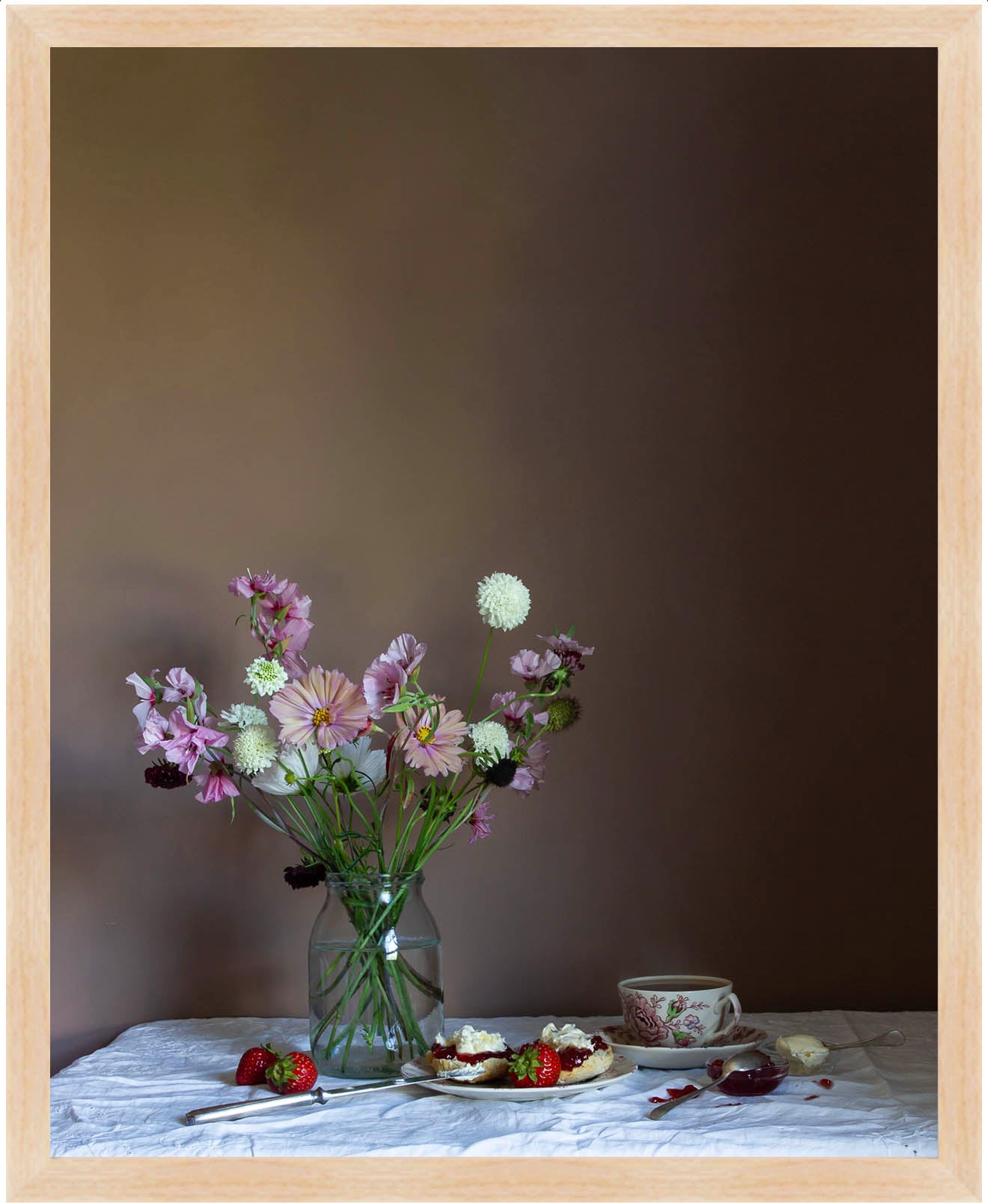 Still life scene with flowers in a vase, a teacup, and a plate of food on a table against a dark wall.