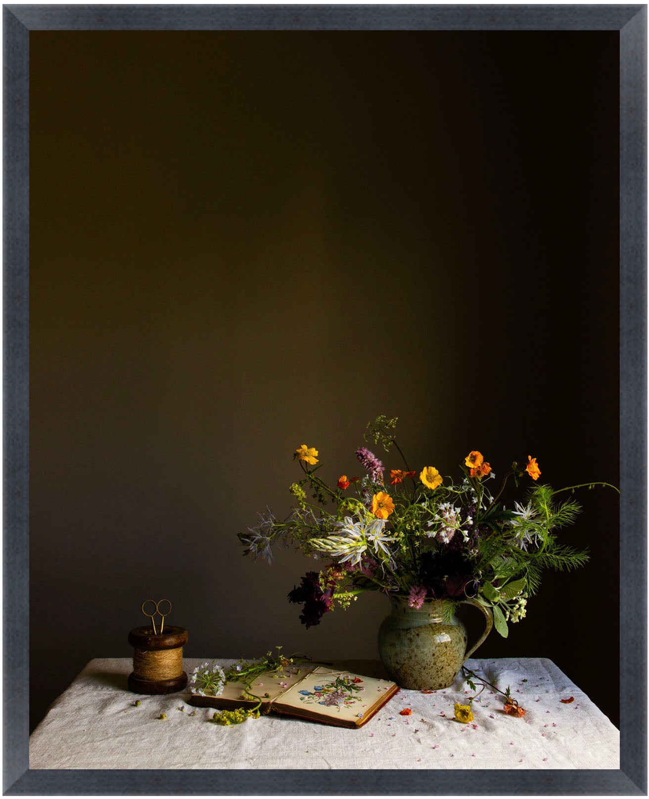 Still life arrangement with flowers and a book on a table against a dark background.  Botanical art.