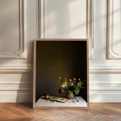 Framed artwork of a still life scene with flowers and books on a table against a dark background.  Floral photography