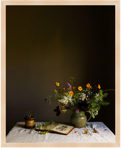 Still life arrangement with flowers and books on a table against a dark background.  floral print