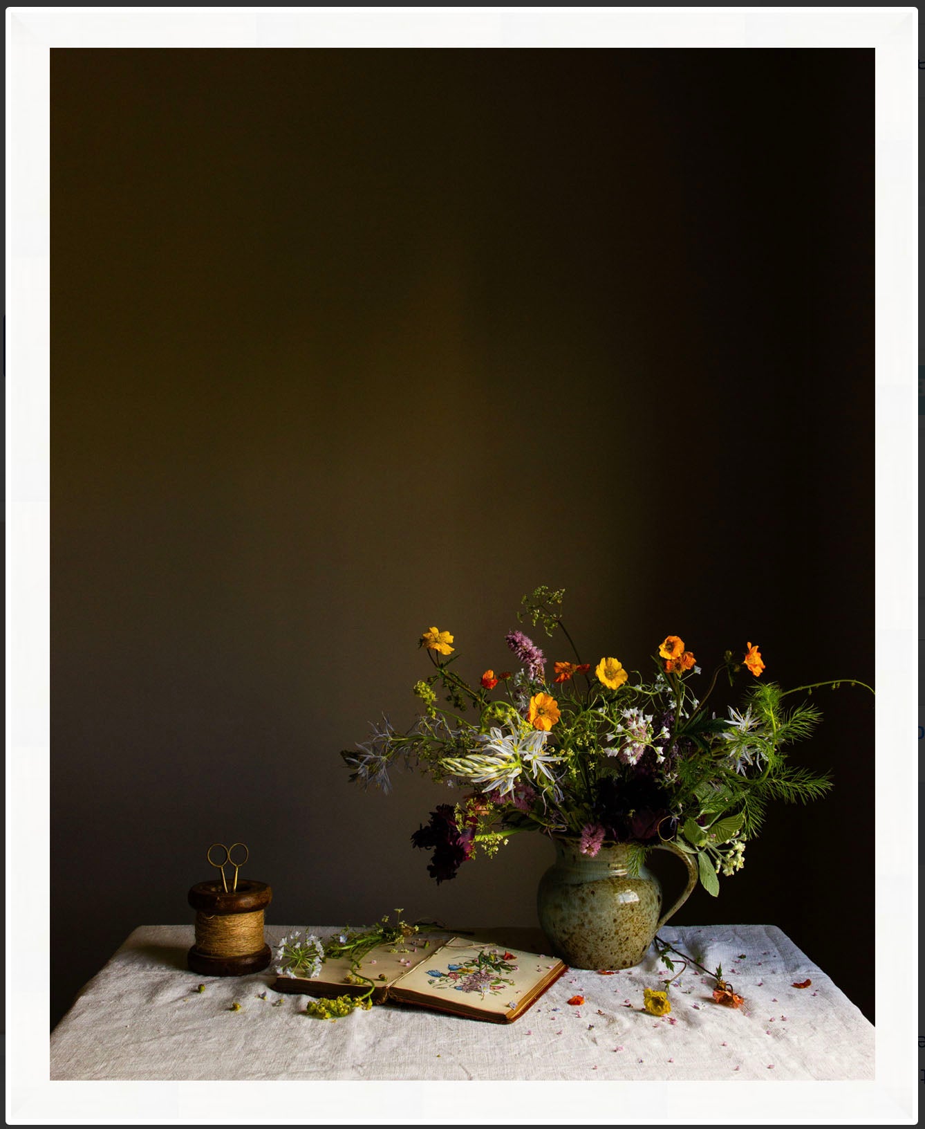Still life arrangement with flowers, a vase, and an open book on a textured surface against a dark background.   Flower artwork