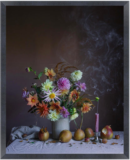 Still life arrangement with flowers, pears, and a candle on a dark background in a black frame