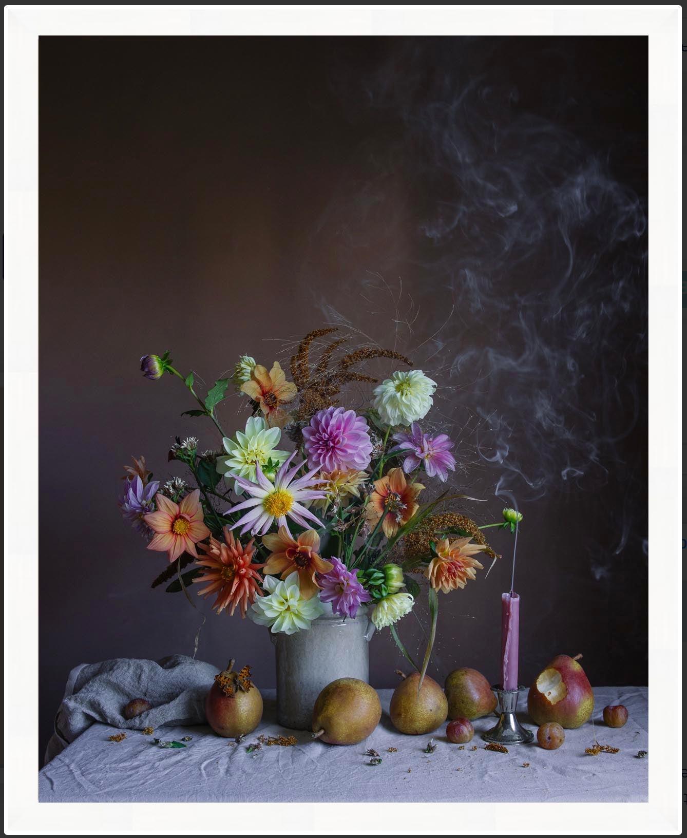 Still life arrangement with flowers, pears, and a candle on a dark background in a white frame
