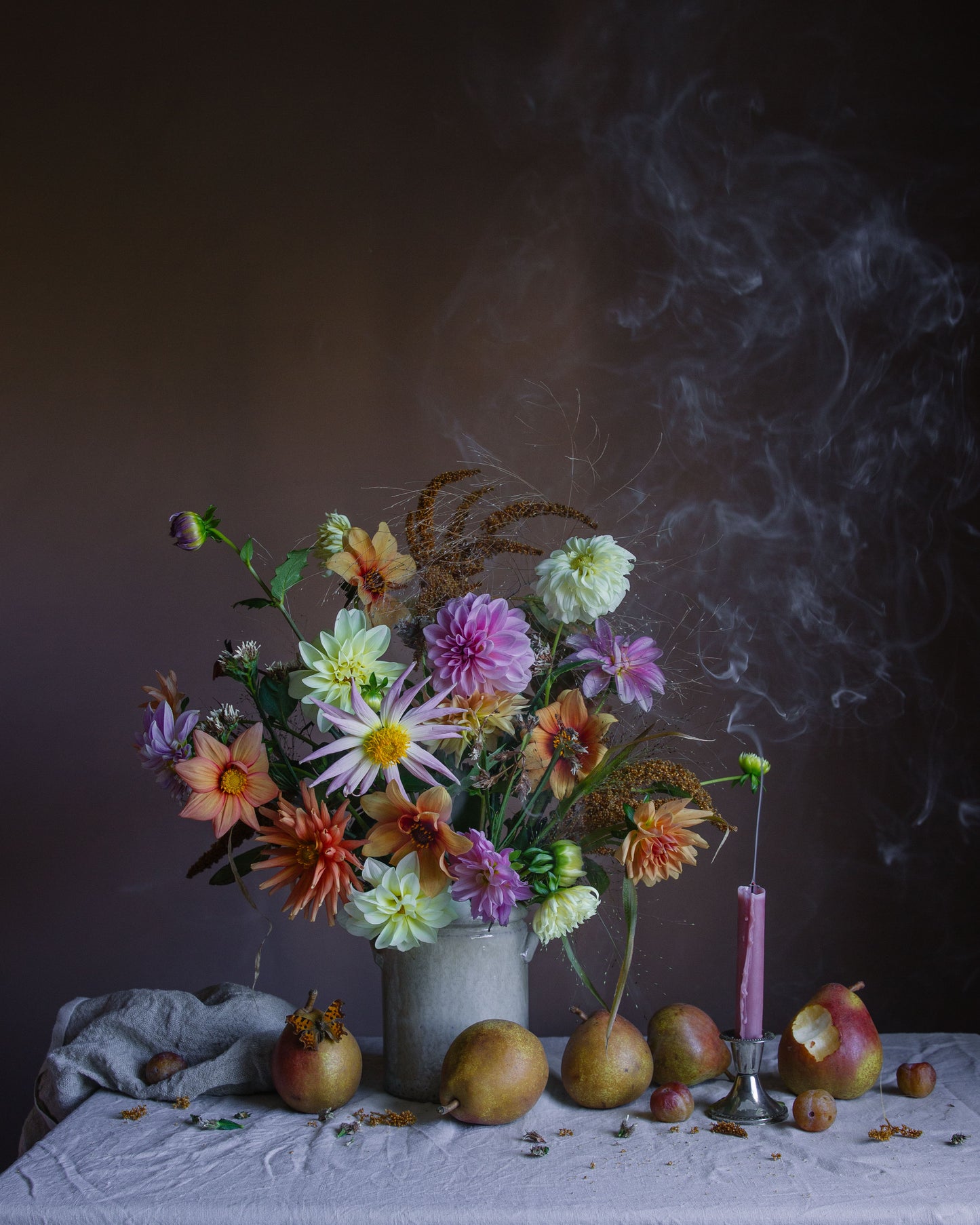 Still life floral arrangement with flowers, pears, and a candle on a dark background