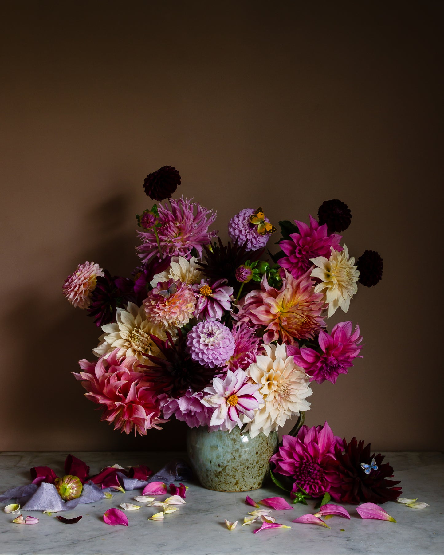 Floral still life of dahlias in a vase on a marble surface with butterflies by fine art photographer Emma Harris
