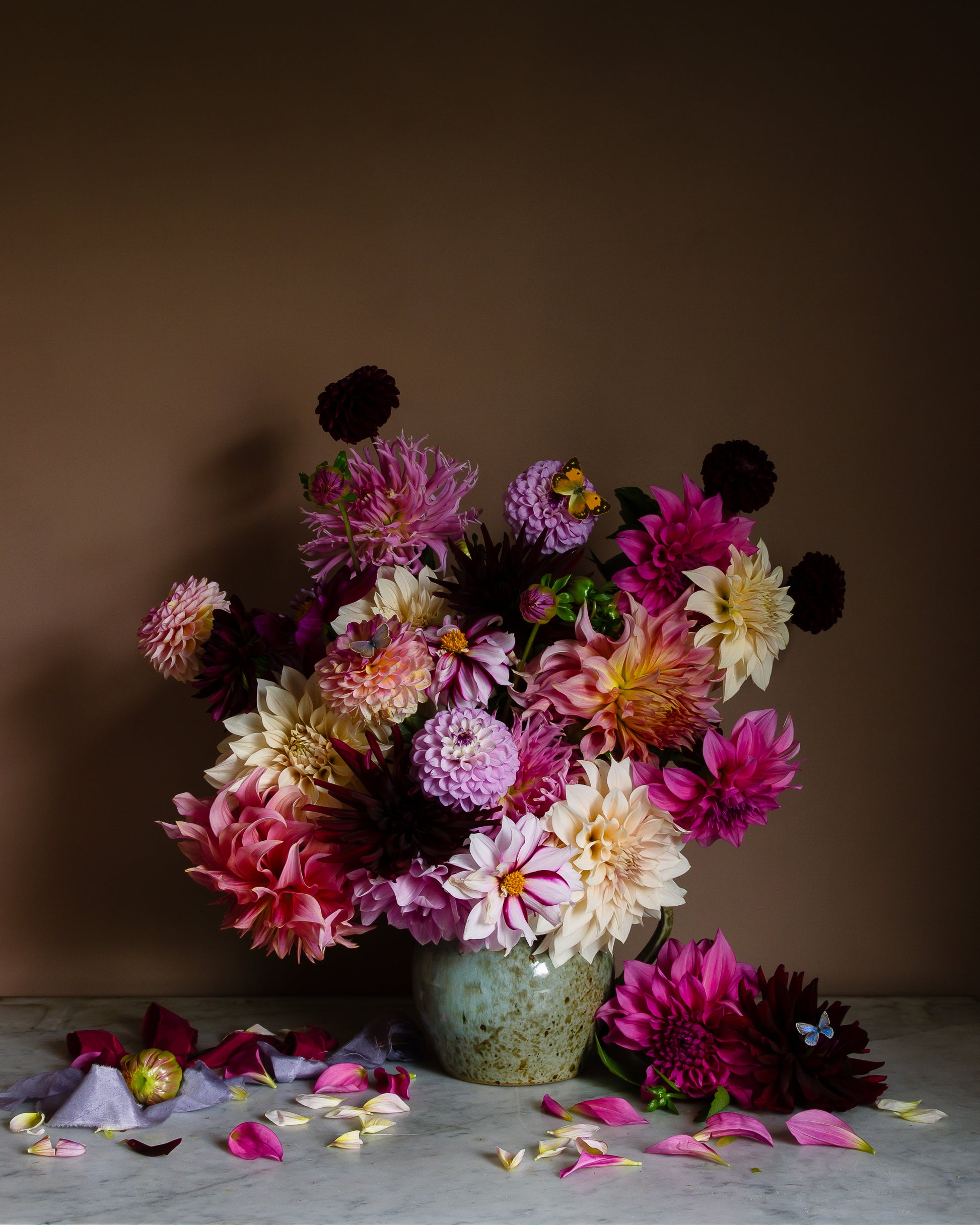Floral still life of dahlias in a vase on a marble surface with butterflies by fine art photographer Emma Harris