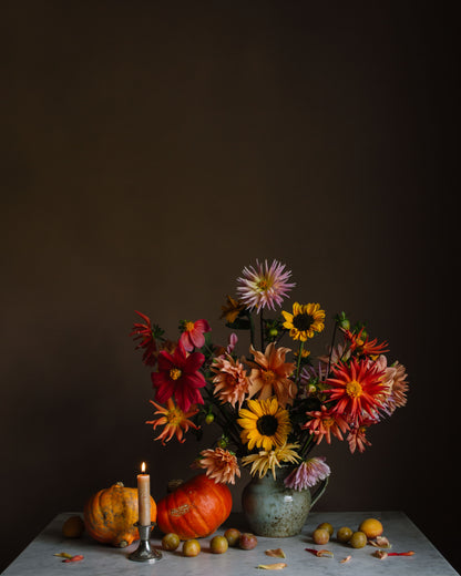 Autumnal still life limited edition fine art photograph with flowers, pumpkins, and a candle on a dark background by photographer Emma Harris