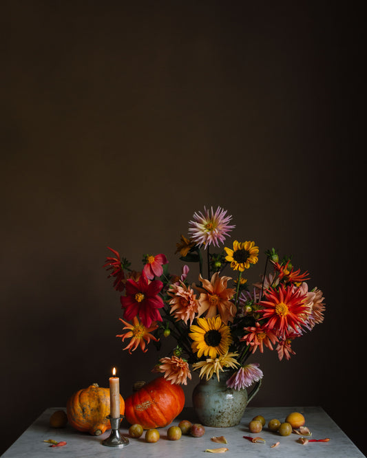 Autumnal still life print with flowers, pumpkins, and a candle on a dark background by Emma Harris