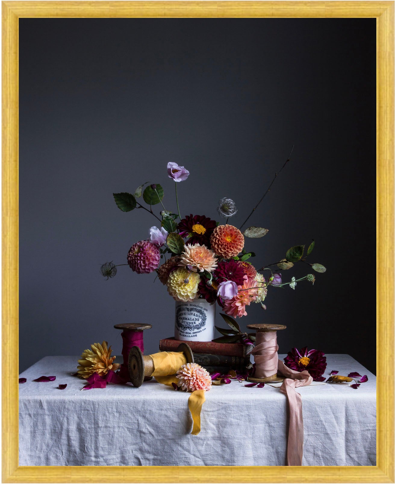 Still life arrangement with flowers and spools on a table against a dark background.   floral artwork