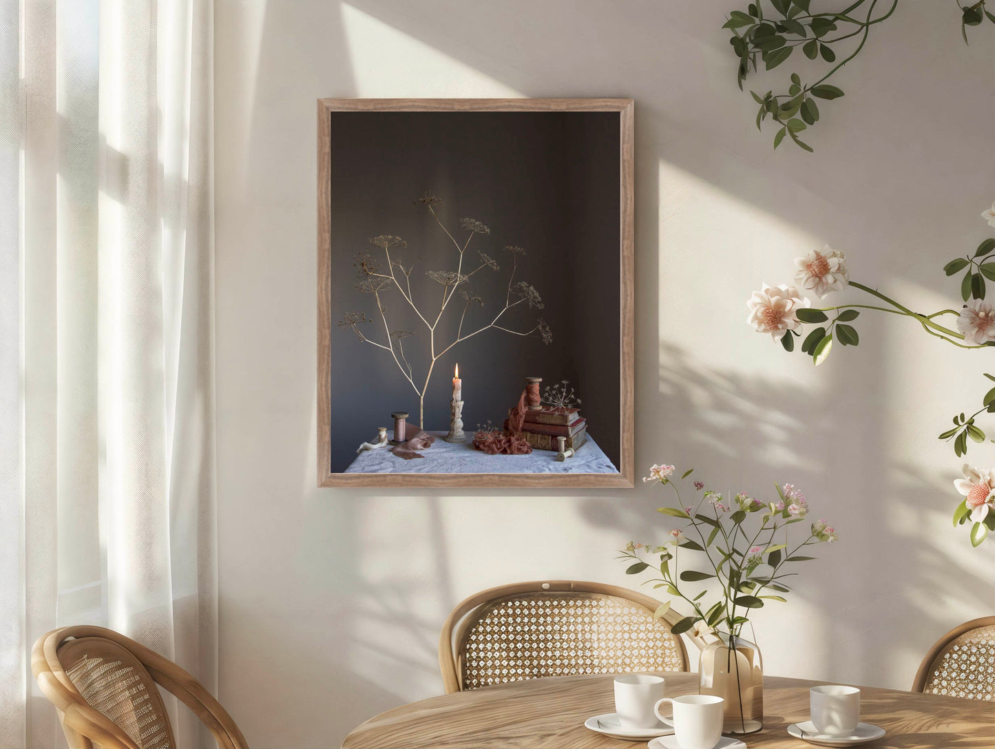 Framed artwork on a wall with a table and chairs below, featuring a vase and flowers.   Floral art.