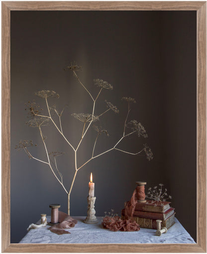 Decorative still life with branches, candle, books, and small figurines on a dark background.   Flower photograph.