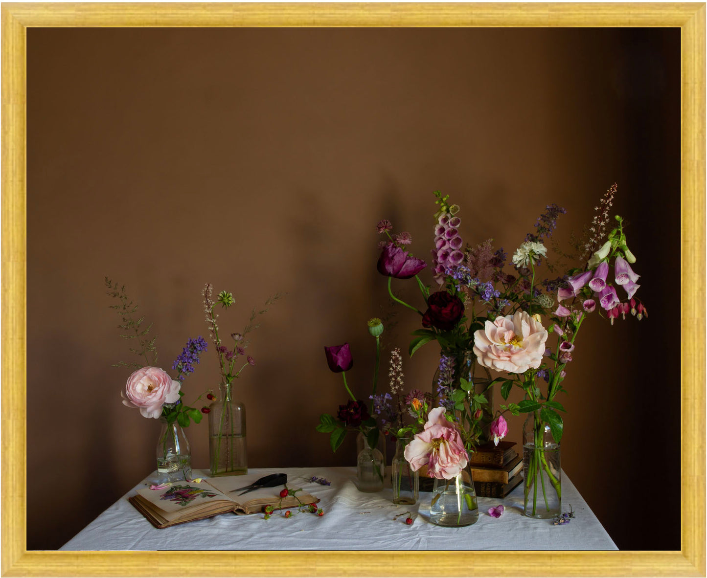 Framed still life arrangement with flowers in vases on a table against a brown background
