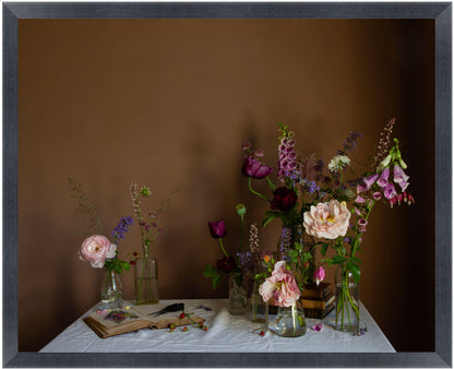 Framed still life arrangement of flowers on a table with a brown background
