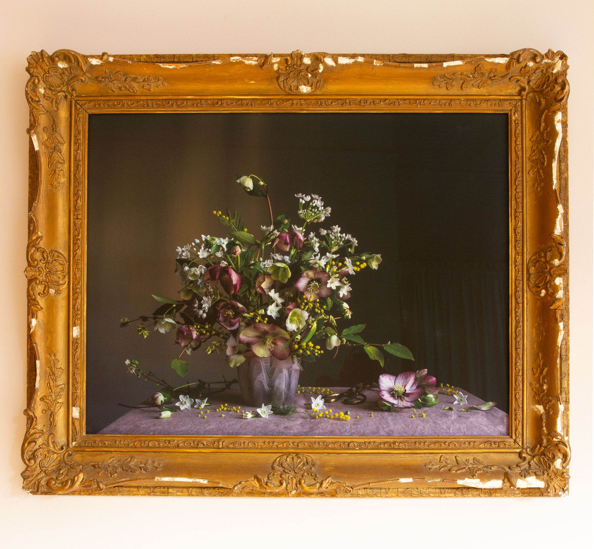 Decorative still life photograph with flowers in a vintage gold frame by Emma Harris on a beige wall.