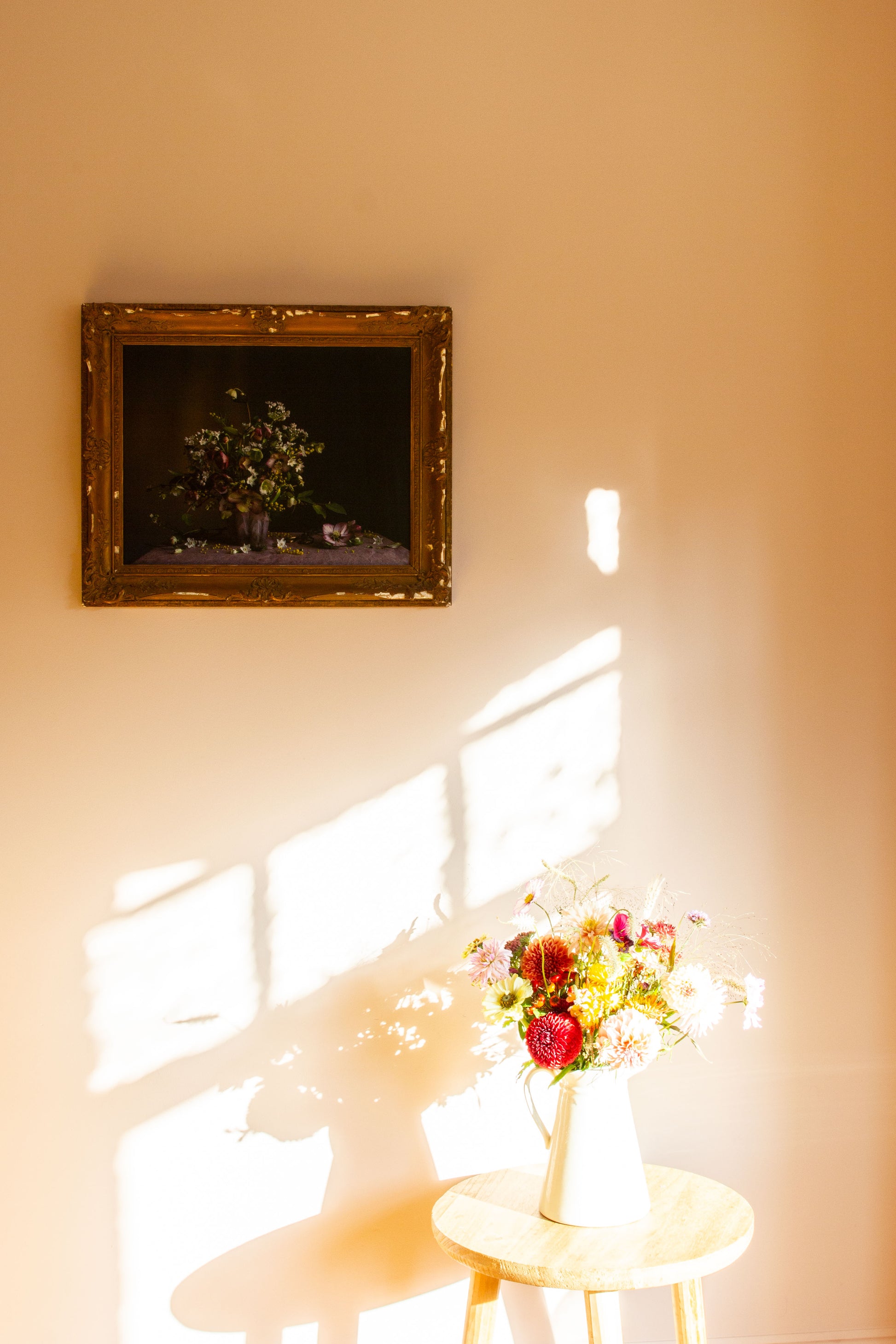 Floral arrangement on a small table with a framed picture on the wall.