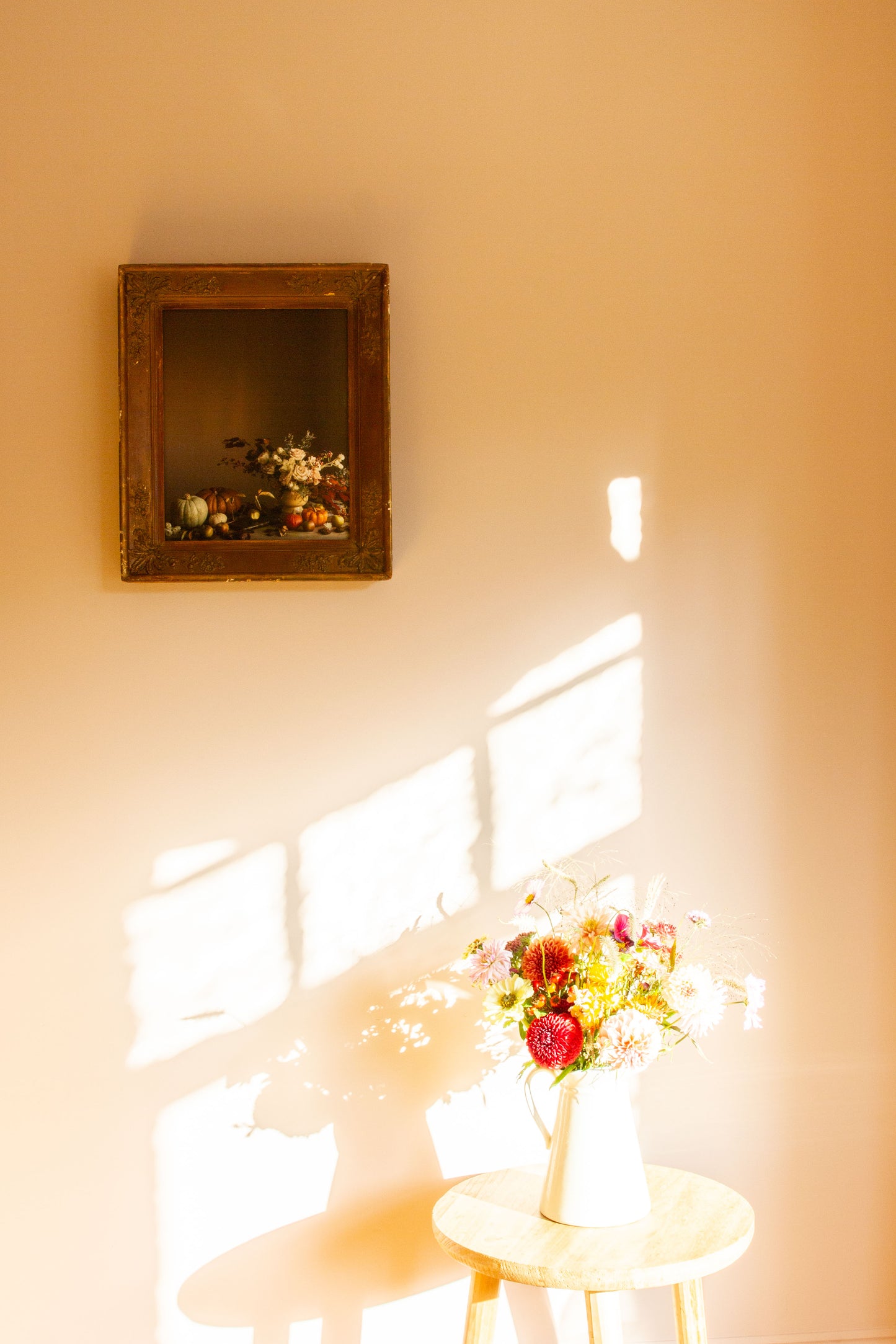 Floral arrangement on a small table alongside floral fine art photograph framed in vintage frame