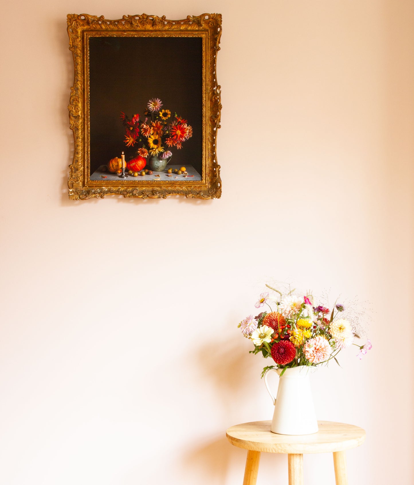Decorative still-life with floral reflection on a wall, accompanied by a vase of flowers on a small table.