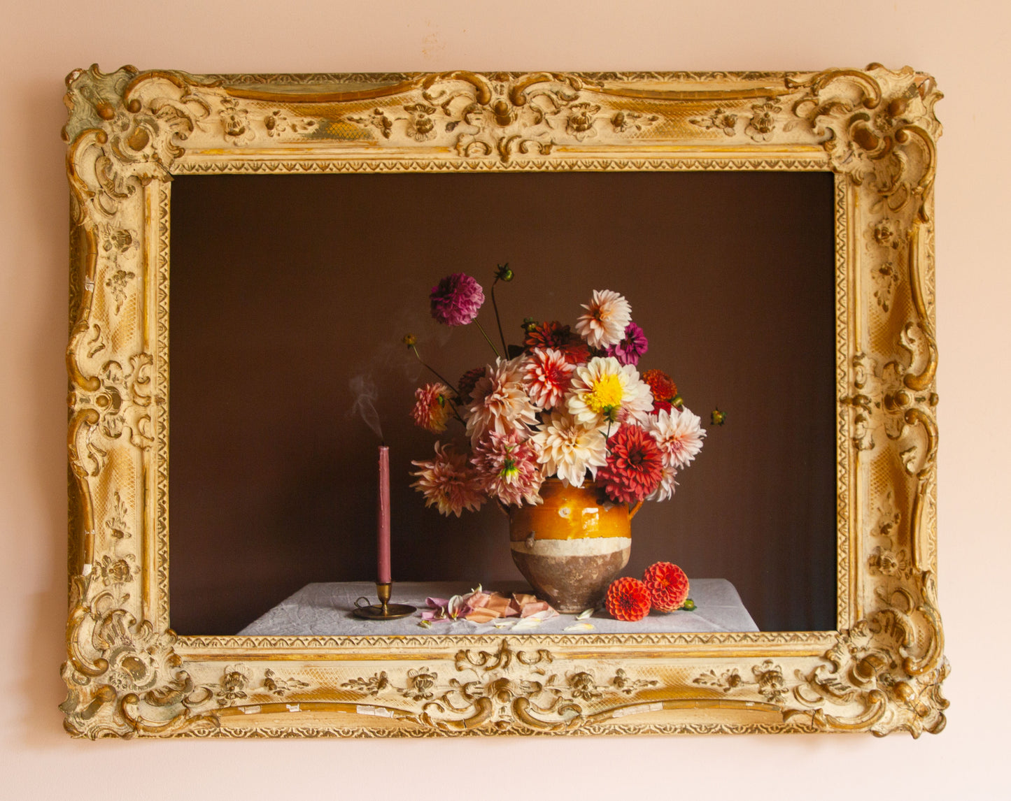 Decorative still life with flowers and a candle in an ornate gold frame.