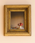 Decorative still life scene with flowers and fruit in a gold frame on a beige wall.