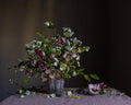 A fine art photograph featuring a botanical arrangement with hellebores and other flowers, predominantly in shades of purple, white, and yellow, printed on fine art paper by Emma Harris