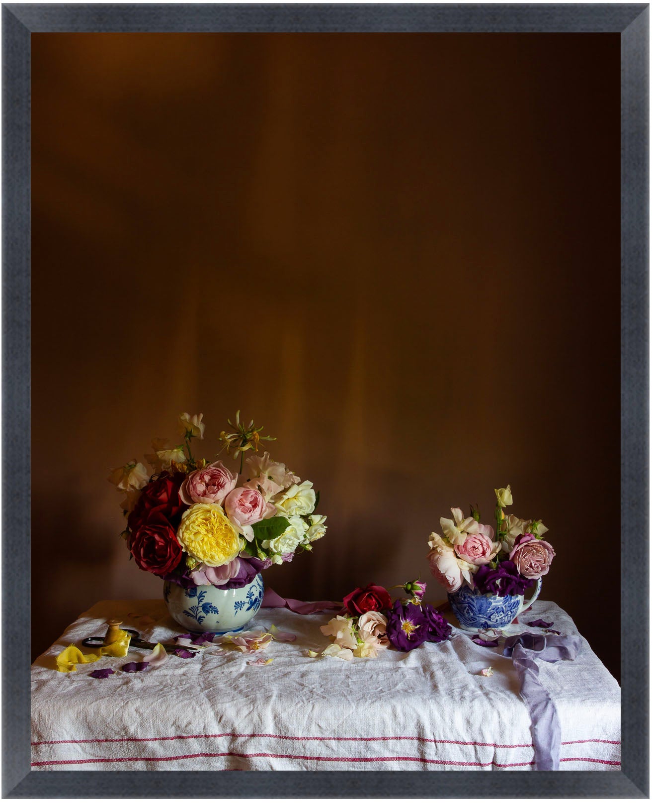 Framed still-life of two floral arrangements on a tablecloth against a dark background by photographer Emma Harris