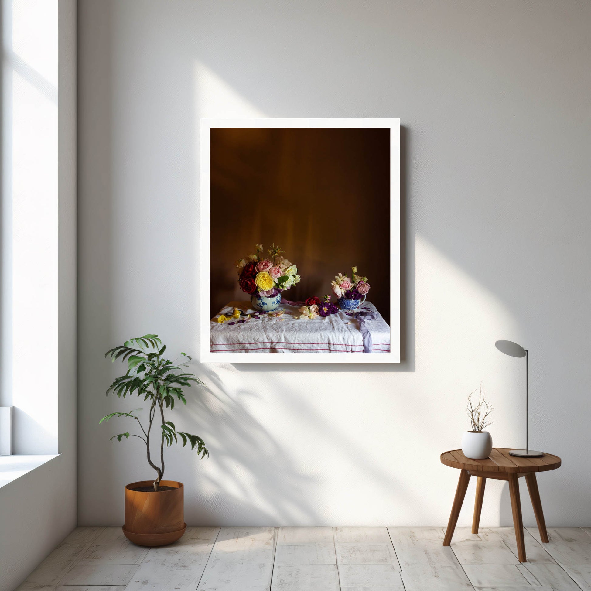 Framed artwork on a wall with a plant and small table in the foreground