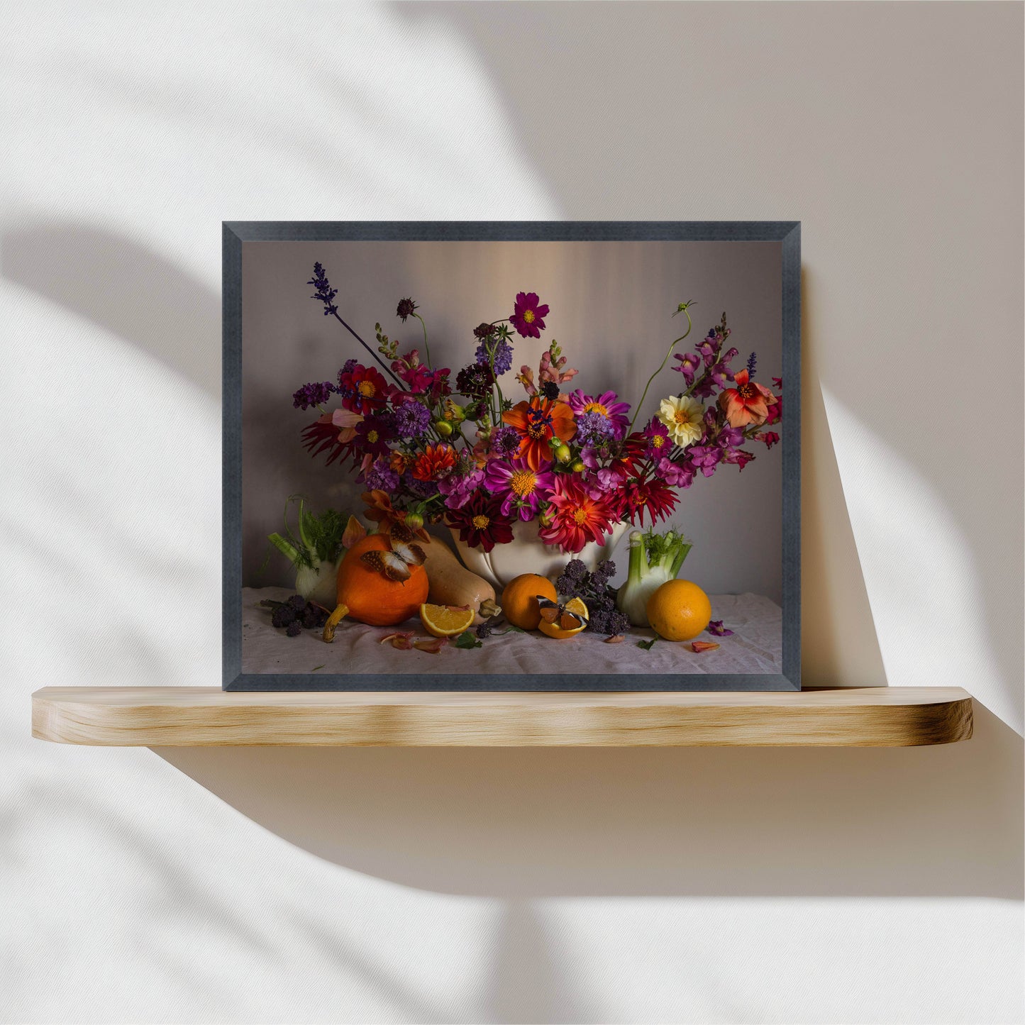 Framed artwork of a colorful floral arrangement with pumpkins on a wooden shelf.