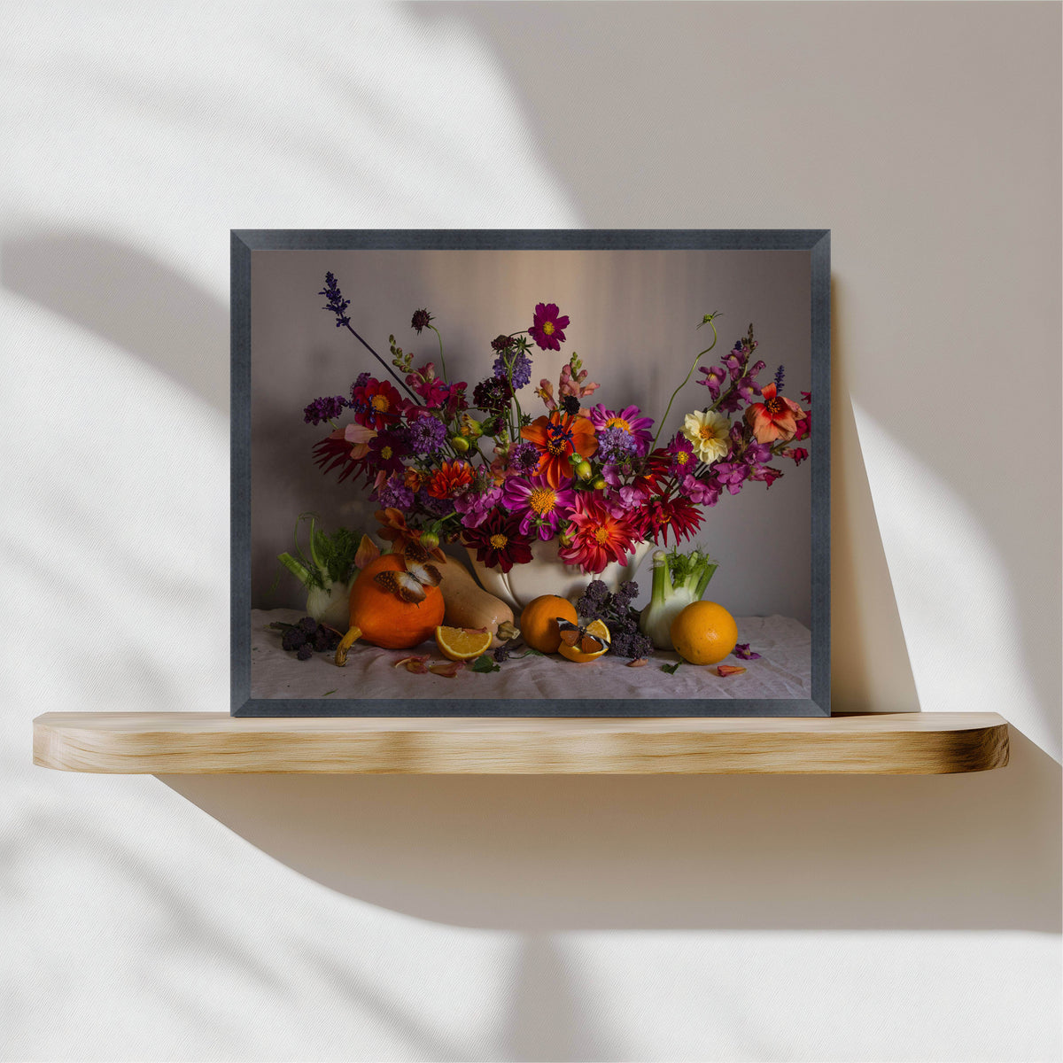 Framed artwork of a colorful floral arrangement with pumpkins on a wooden shelf.