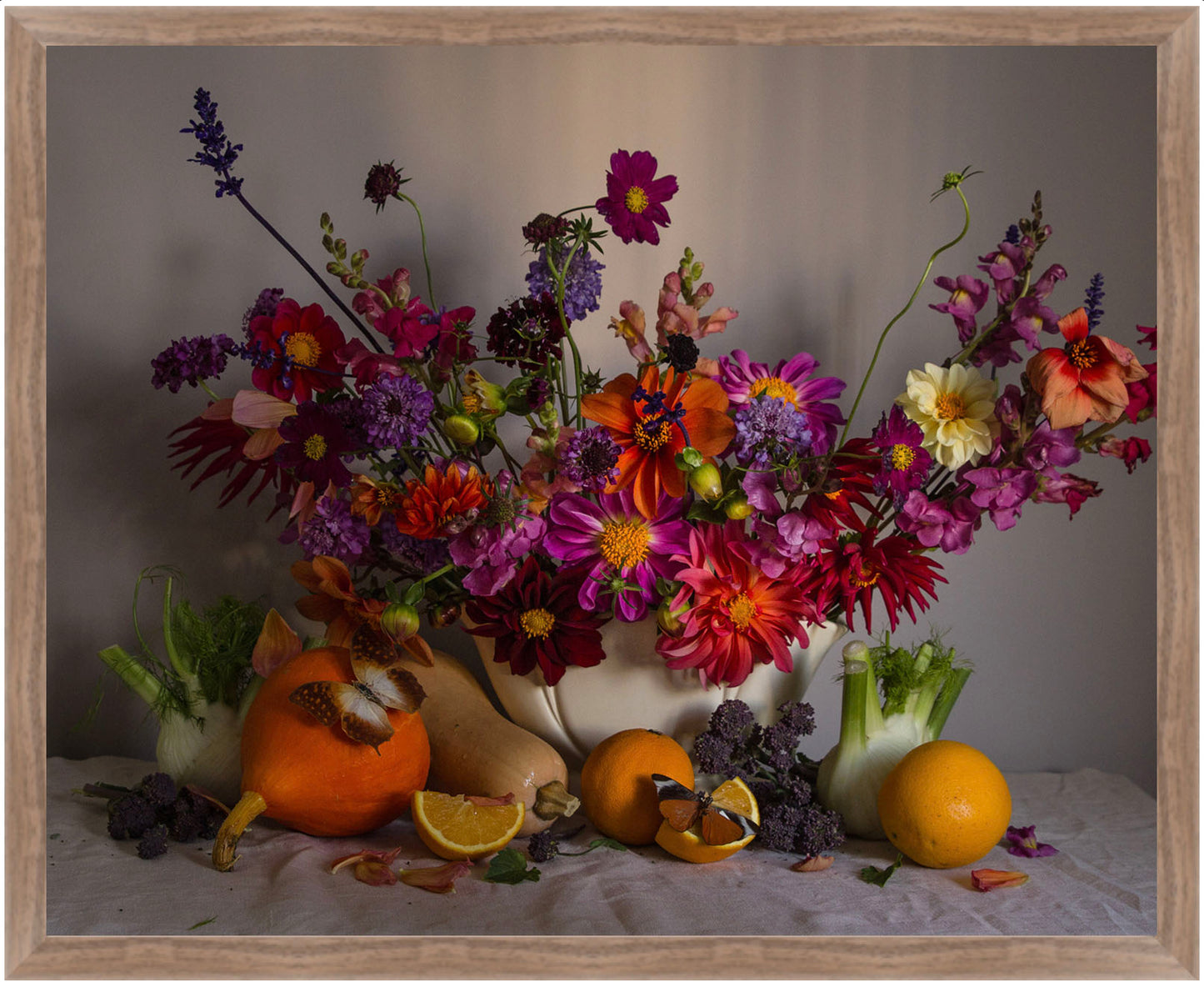 Framed still life with flowers, fruits, and vegetables on a neutral background