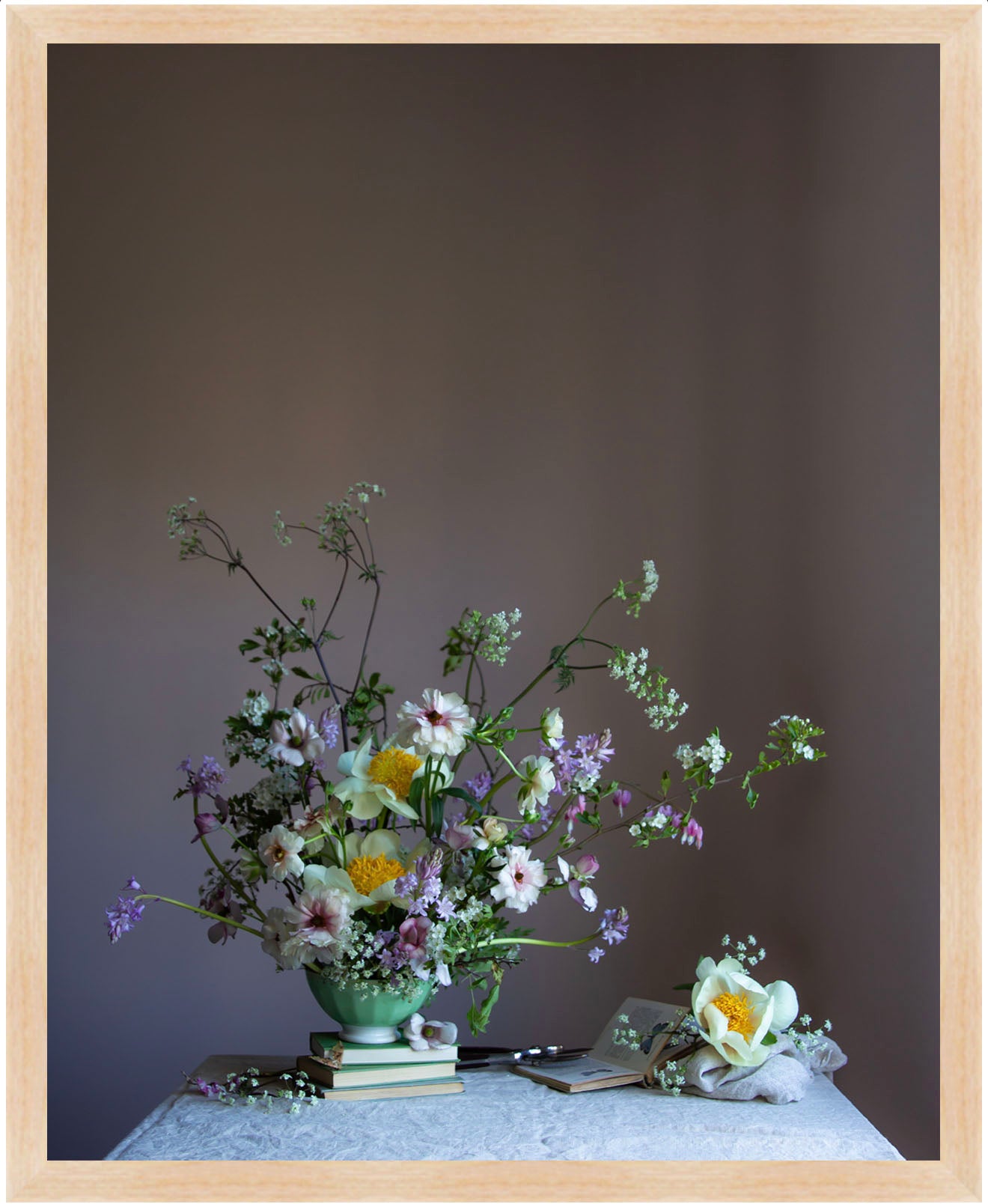 Floral arrangement in a green vase on a table with a plain background.   Floral print