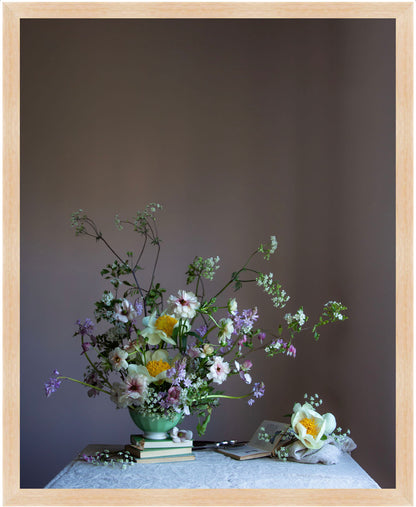 Floral arrangement in a green vase on a table with a plain background.   Floral print