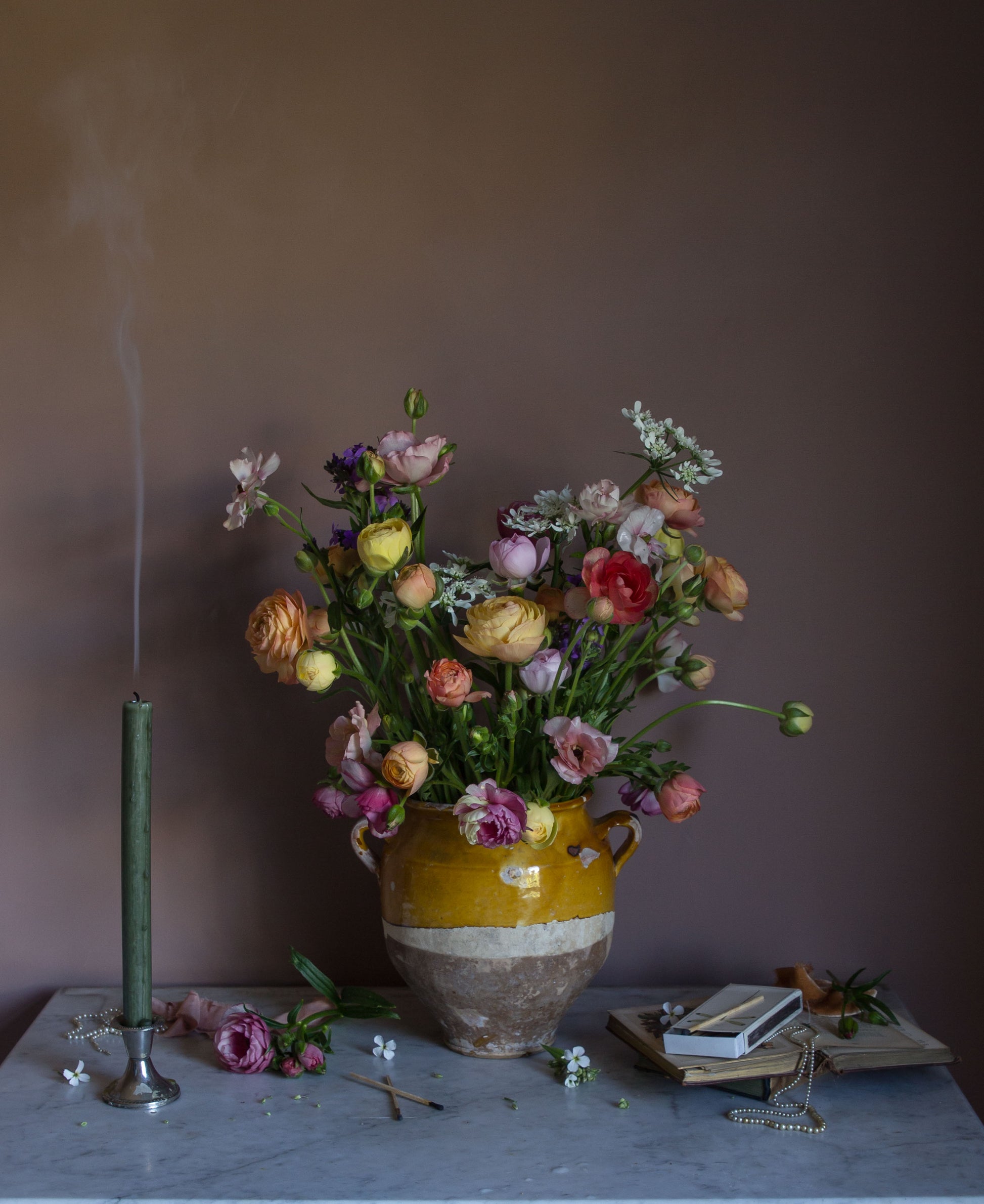 Floral still life print of ranunculus and a smoking candle on a marble surface
