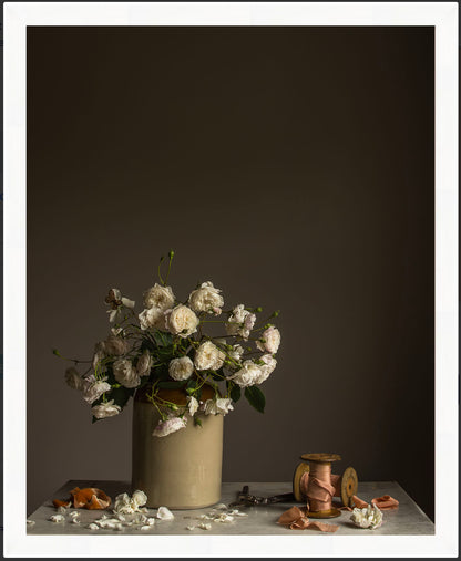 Vase with white flowers on a table against a dark background.   Flower art