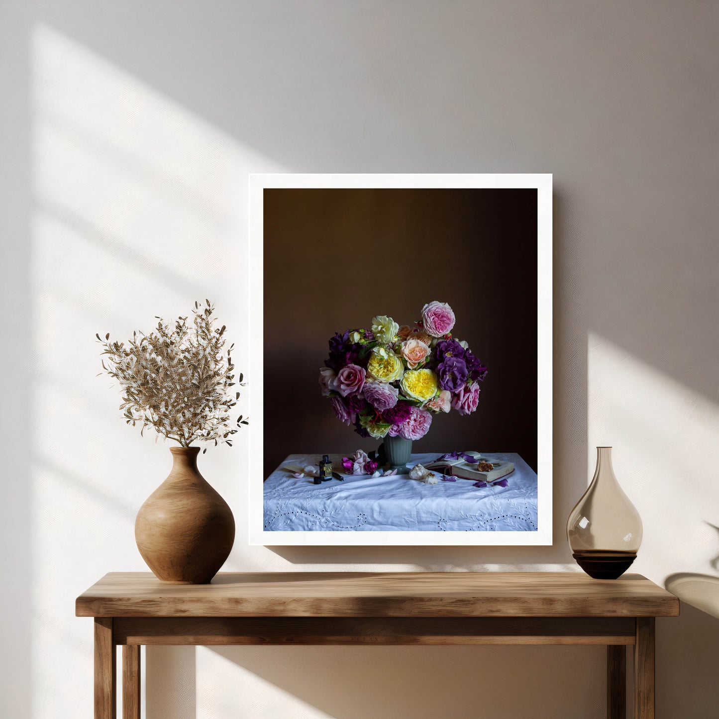 Framed still-life photograph of a floral arrangement on a wooden table with decorative vases.