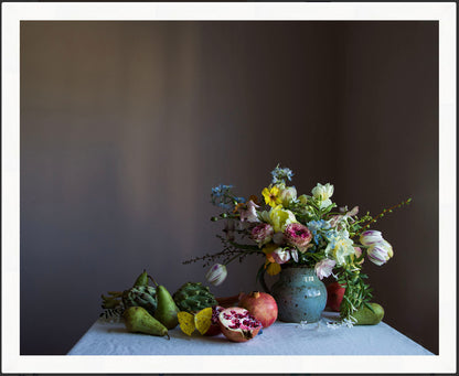 Vase of flowers with pears and a pomegranate on a table against a dark background. Floral art