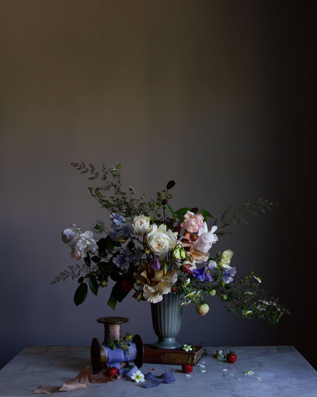 A fine art photograph featuring a floral arrangement with roses and other flowers in a vase, set against a dark background by photographer Emma Harris.   Floral art