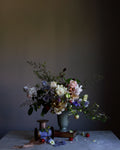 A fine art photograph featuring a floral arrangement with roses and other flowers in a vase, set against a dark background by photographer Emma Harris.   Floral art