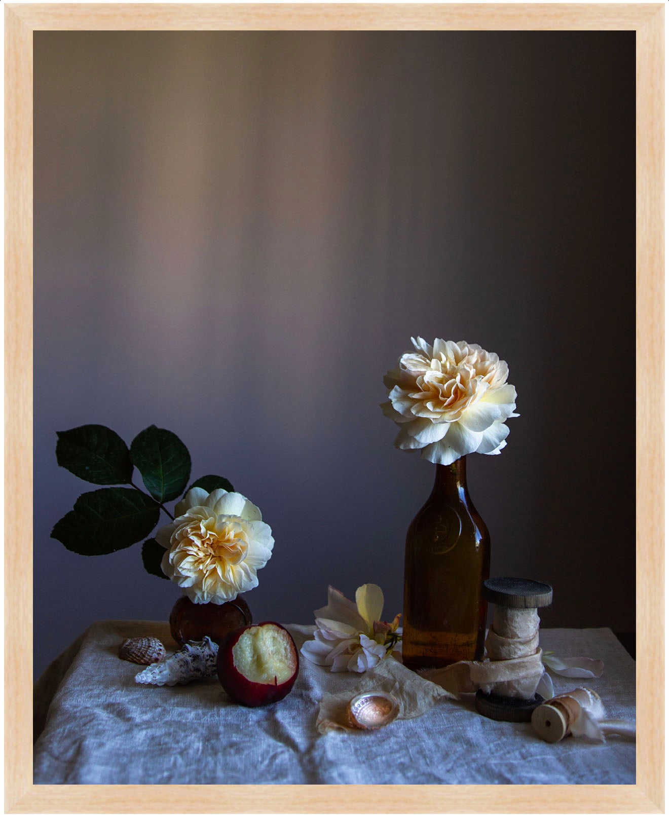 Still life arrangement with flowers in bottles on a textured surface against a dark background.  Flower art by Emma Harris