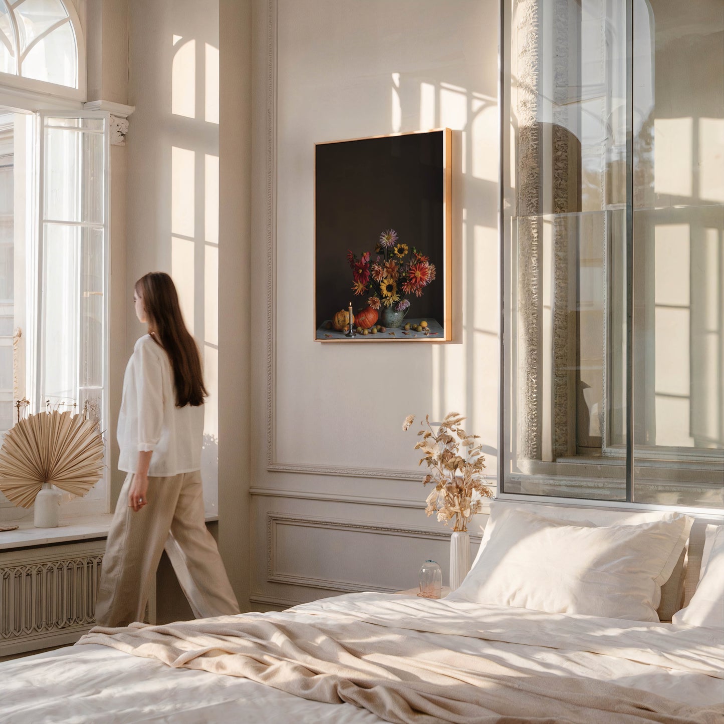 Woman in a bedroom looking at a picture of flowers on the wall.