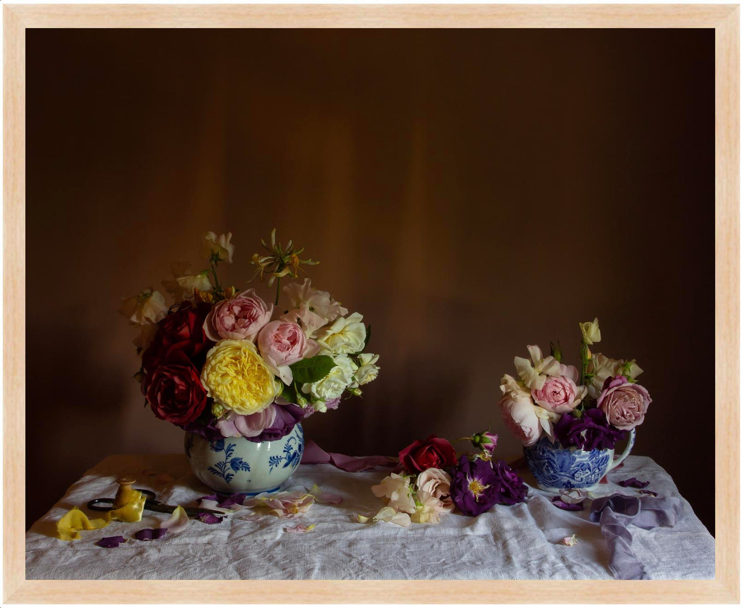 Framed floral still-life art showing Two floral arrangements in jugs on a textured surface with a dark background in an oak frame